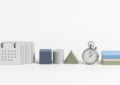 Minimal white-background objects showing calendar tiles, prototype blocks, and a stopwatch for faster internal app delivery.
